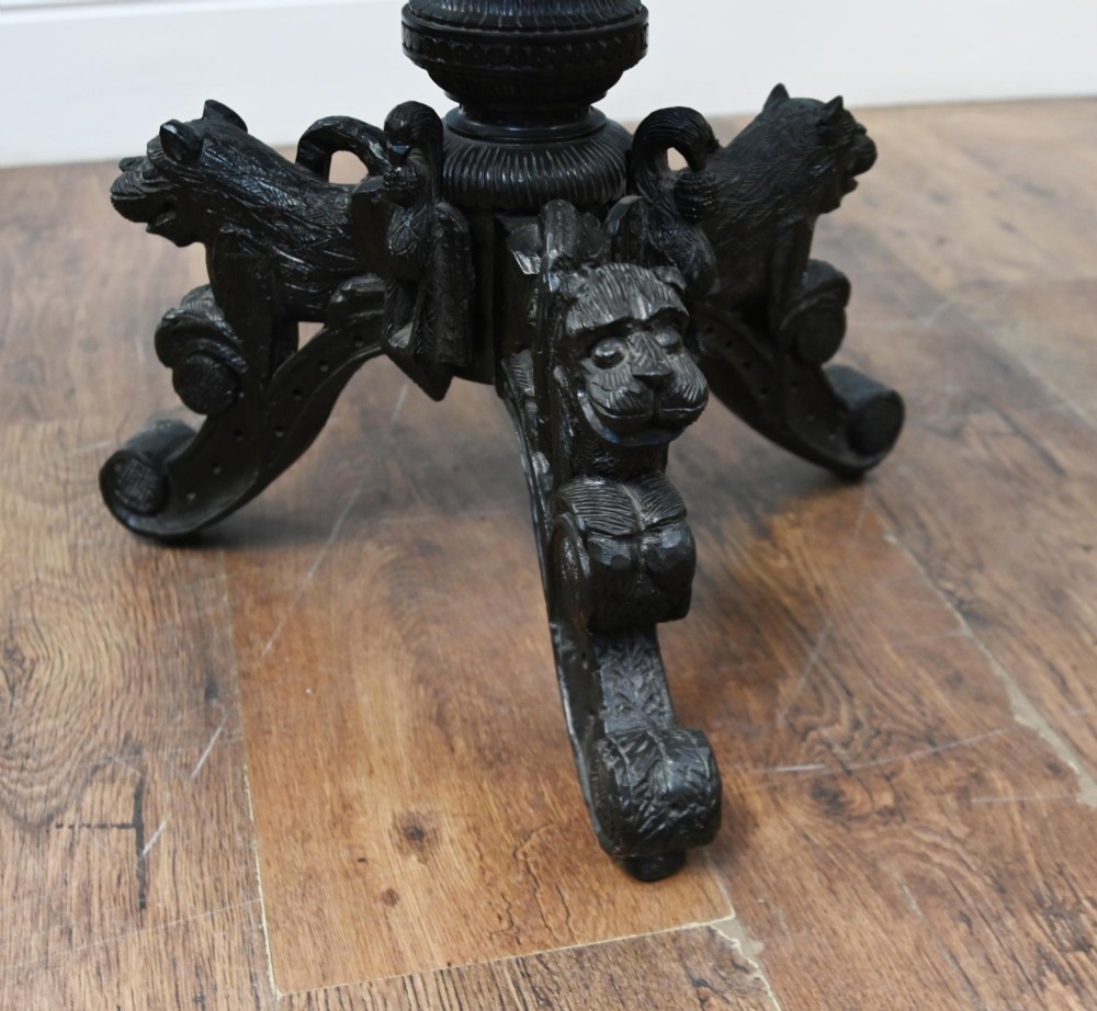 An antique octagonal dark hardwood side table featuring intricate pierced floral carvings around the apron and a central turned pedestal supported by three mythical carved beast legs. View VII