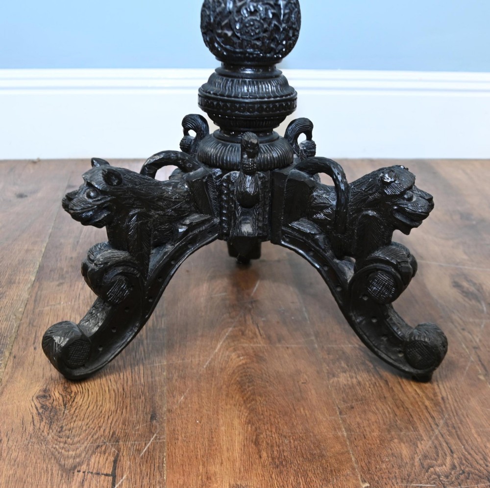 An antique octagonal dark hardwood side table featuring intricate pierced floral carvings around the apron and a central turned pedestal supported by three mythical carved beast legs. View IX