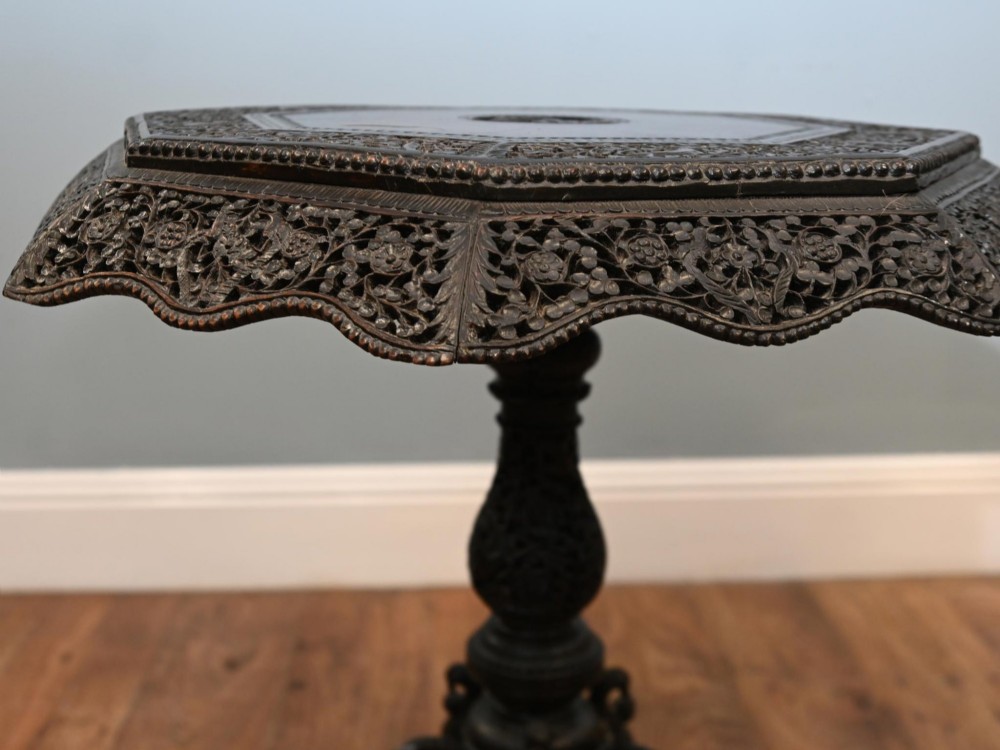 An antique octagonal dark hardwood side table featuring intricate pierced floral carvings around the apron and a central turned pedestal supported by three mythical carved beast legs. View XI