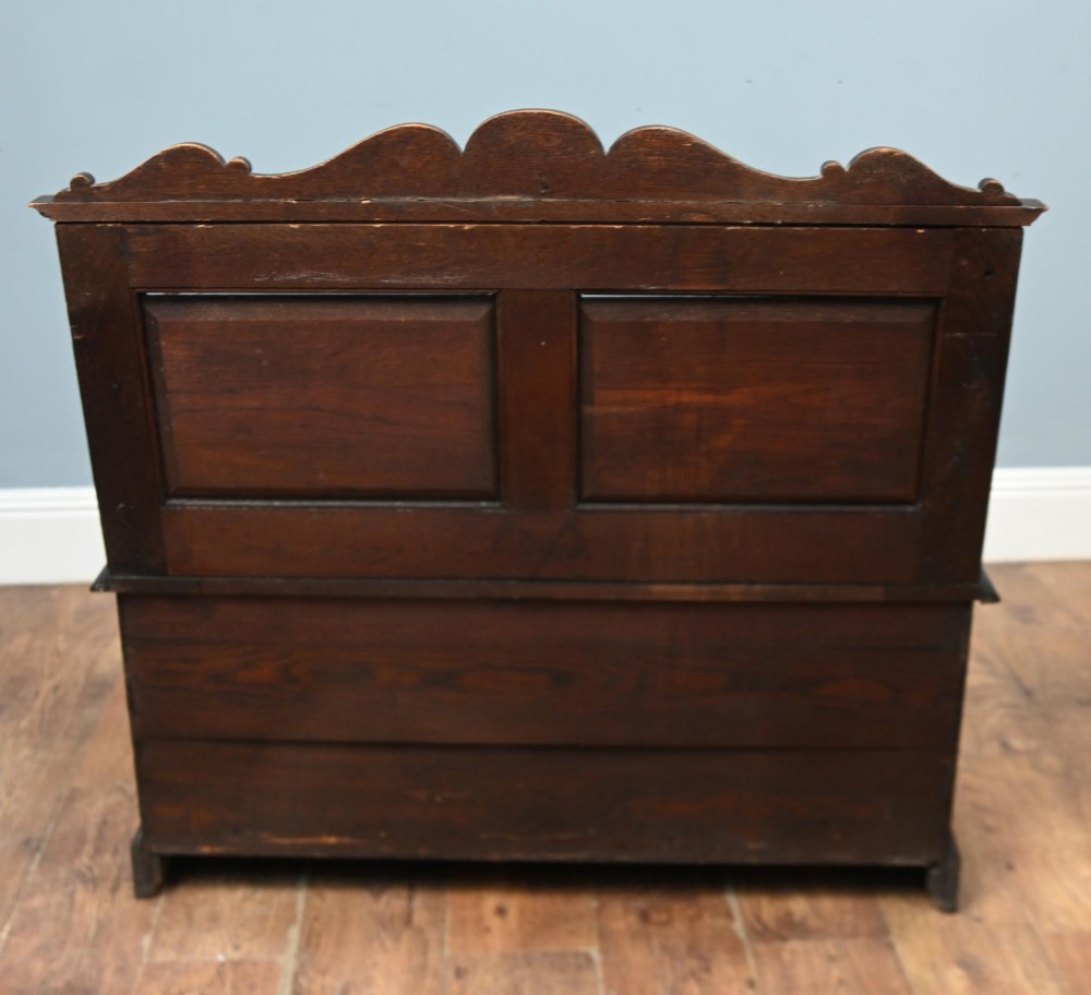 A Victorian dark oak carved settle featuring carved lion head armrests, detailed floral and geometric back panels, and a lift-up storage seat. View XI