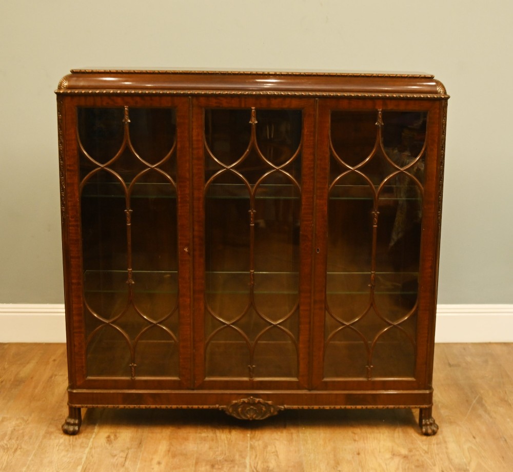 A Chippendale Revival mahogany display cabinet featuring three astragal glazed doors and carved ball and claw feet. View II