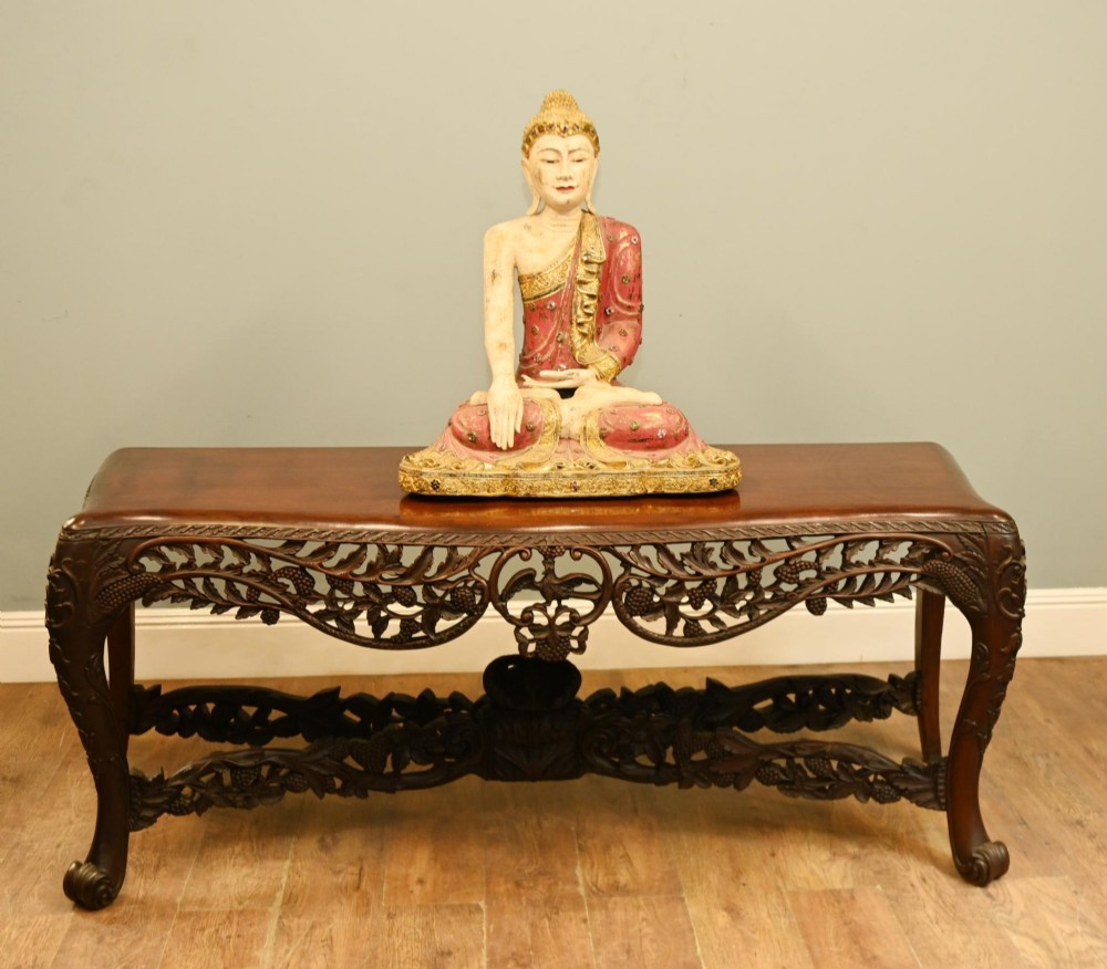 A dark hardwood Qing Dynasty console table featuring intricate carved openwork aprons and scrolled cabriole legs.