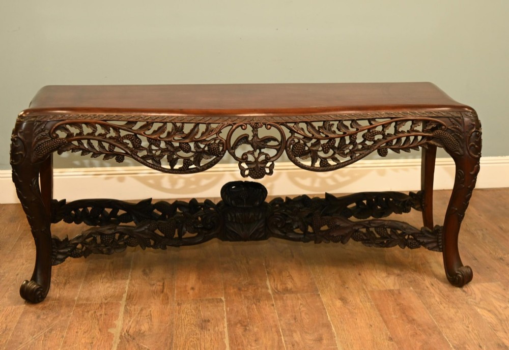 A dark hardwood Qing Dynasty console table featuring intricate carved openwork aprons and scrolled cabriole legs. View IX