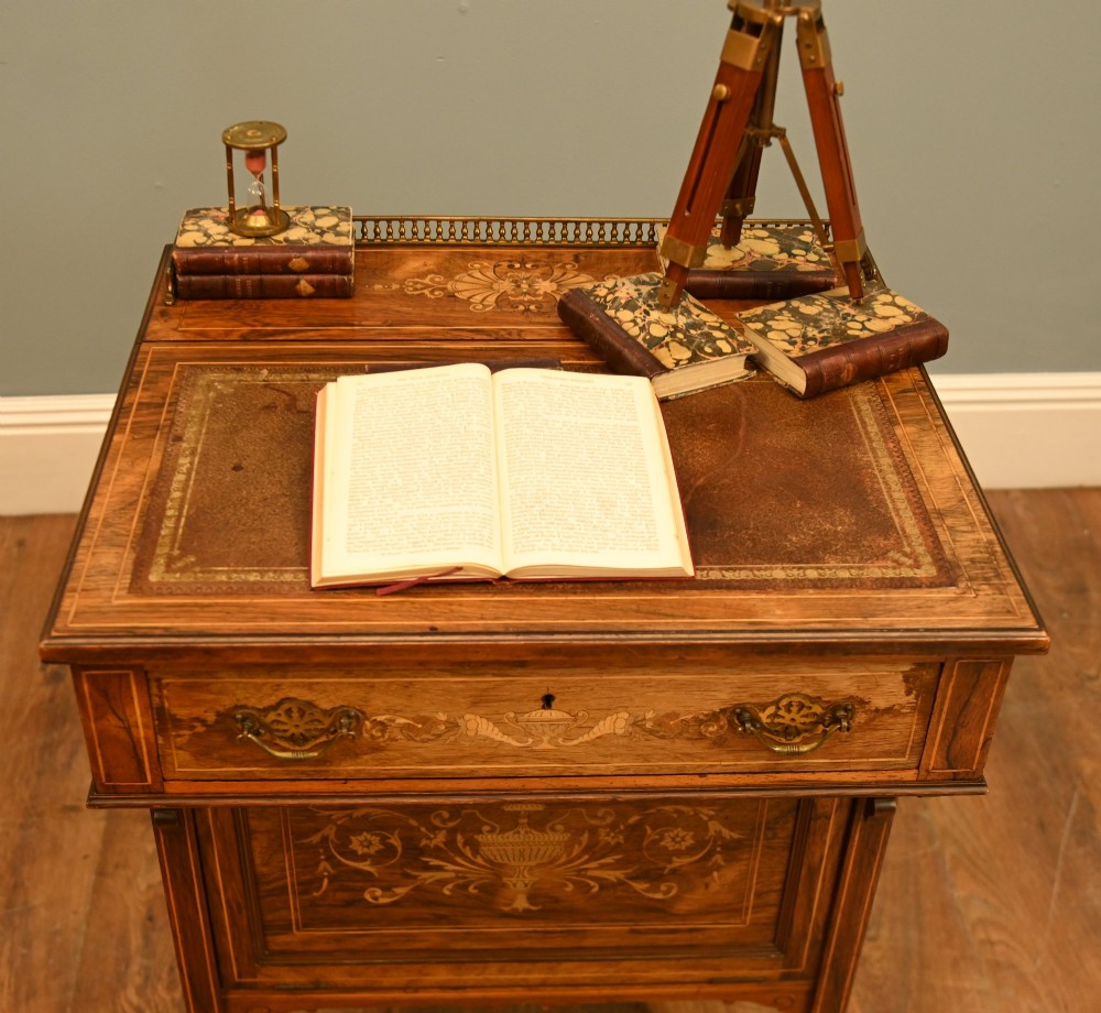 An Edwardian mahogany Davenport desk with urn marquetry inlays, a leather writing slope, brass gallery rim, and legs on castors. View II