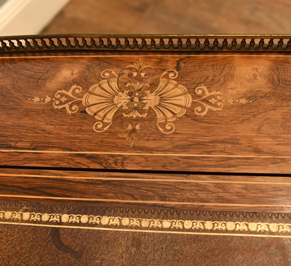 An Edwardian mahogany Davenport desk with urn marquetry inlays, a leather writing slope, brass gallery rim, and legs on castors. View VI