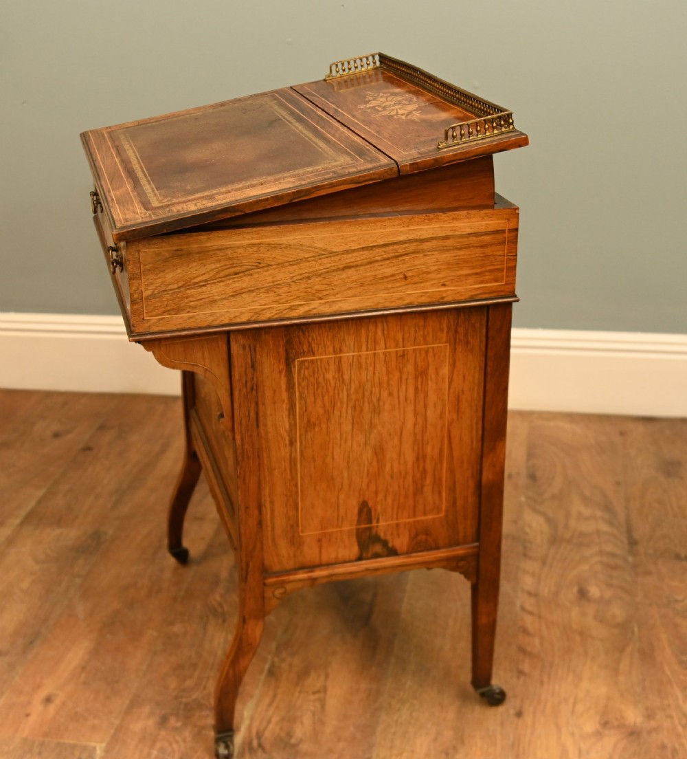 An Edwardian mahogany Davenport desk with urn marquetry inlays, a leather writing slope, brass gallery rim, and legs on castors. View VII