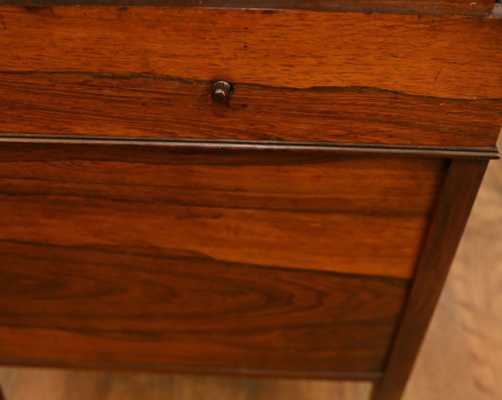 An Edwardian mahogany Davenport desk with urn marquetry inlays, a leather writing slope, brass gallery rim, and legs on castors. View IX