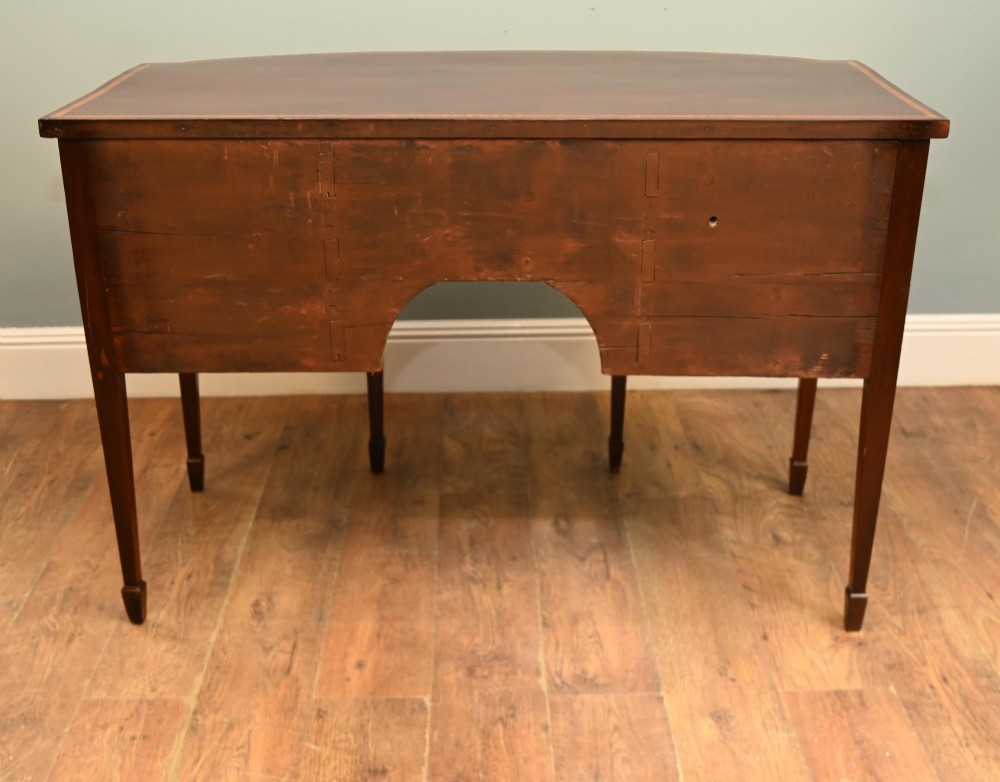An Edwardian mahogany bowfront sideboard with satinwood inlaid borders, three central drawer and cabinet sections, and brass lion mask ring handles on tapered legs. View XIII
