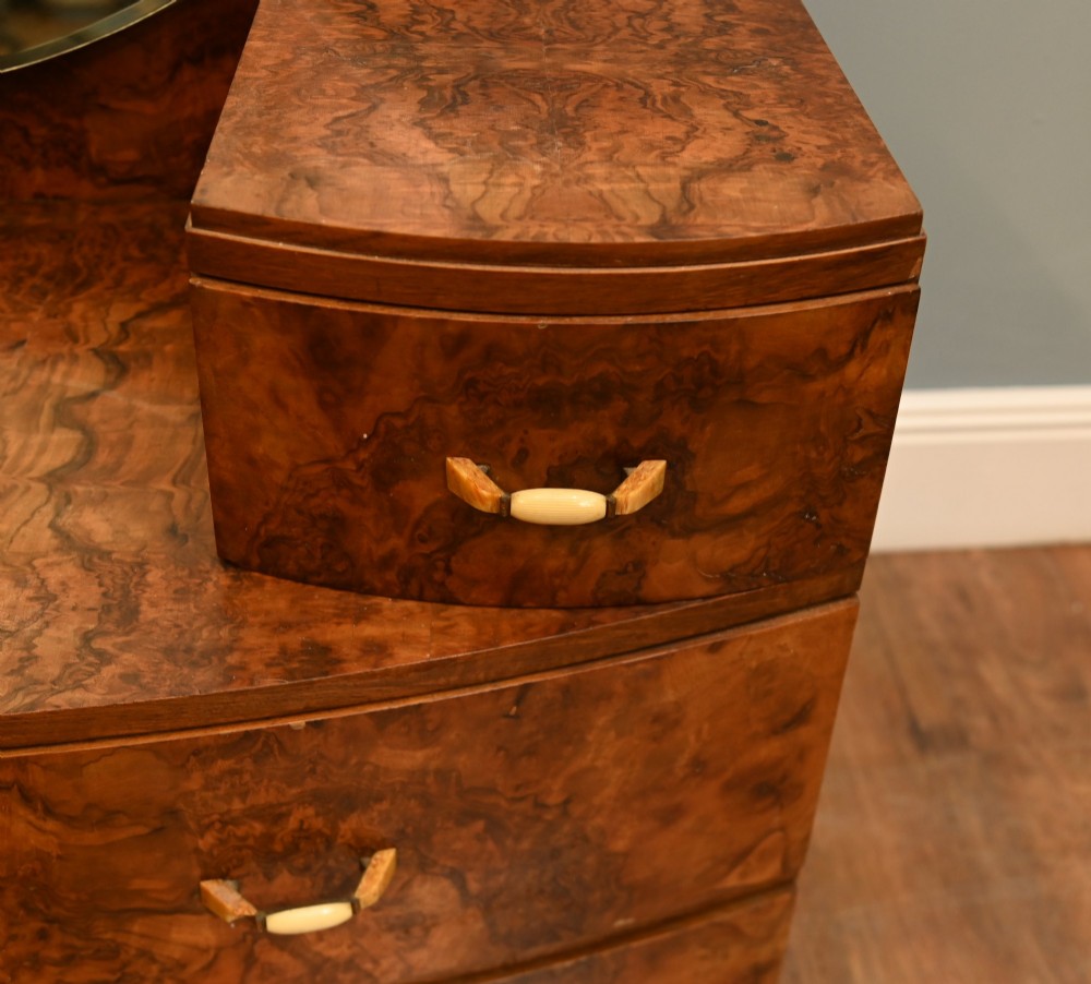 An Art Deco burr walnut dressing table featuring a large circular mirror mounted behind six bow-fronted drawers. View V