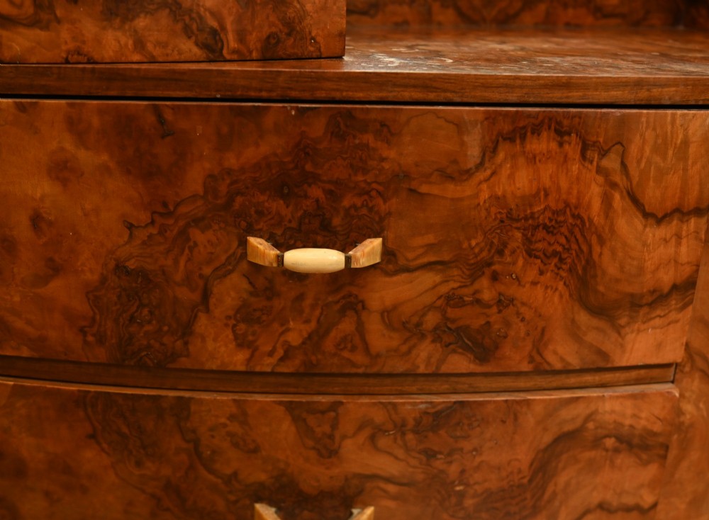 An Art Deco burr walnut dressing table featuring a large circular mirror mounted behind six bow-fronted drawers. View VI
