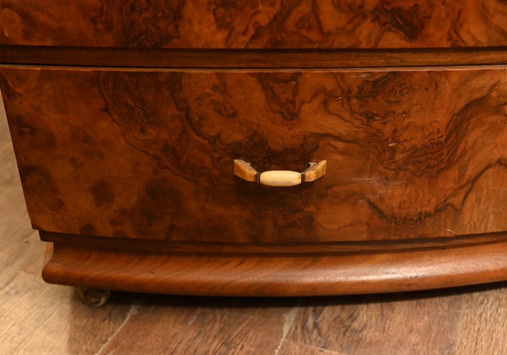 An Art Deco burr walnut dressing table featuring a large circular mirror mounted behind six bow-fronted drawers. View VIII