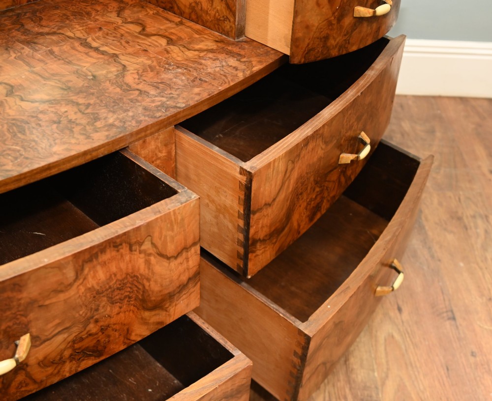 An Art Deco burr walnut dressing table featuring a large circular mirror mounted behind six bow-fronted drawers. View XI