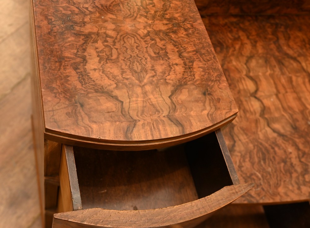An Art Deco burr walnut dressing table featuring a large circular mirror mounted behind six bow-fronted drawers. View XII