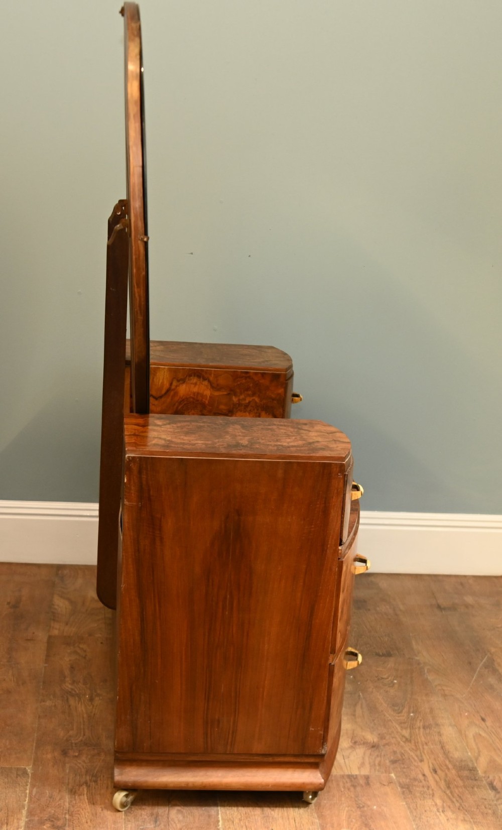 An Art Deco burr walnut dressing table featuring a large circular mirror mounted behind six bow-fronted drawers. View XIII