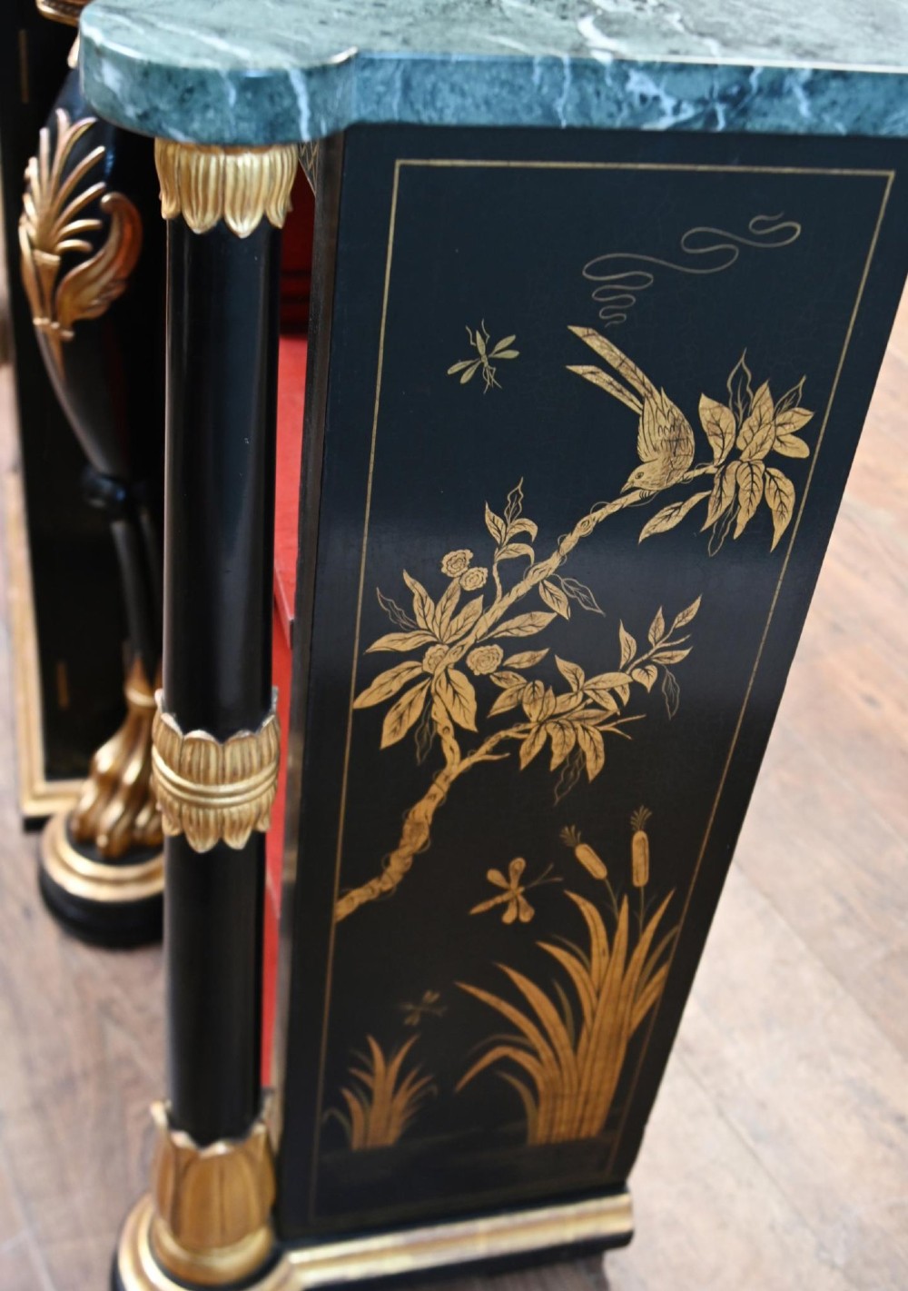 A Regency Revival side cabinet featuring a green marble top, a central black lacquer door decorated with gilded Chinoiserie artwork, and flanking open shelves with red interiors. View V