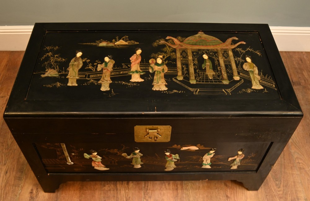 A black lacquered rectangular wooden chest embellished with raised soapstone figures and landscape scenes, fitted with an etched brass lock plate. View V