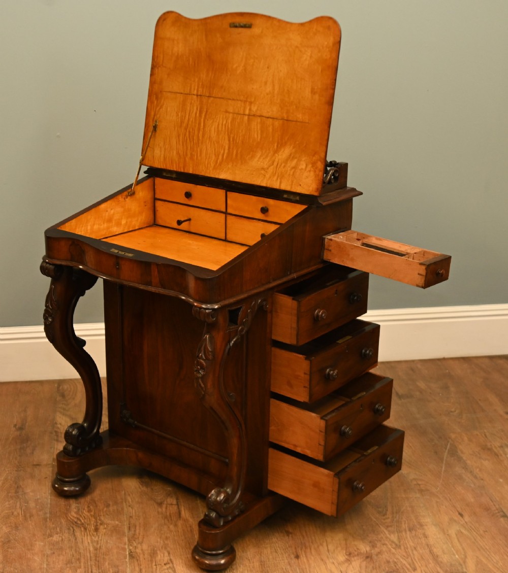A Victorian mahogany Davenport desk featuring a sloped leather writing top, carved cresting rail, serpentine front supports, and side drawers. View II