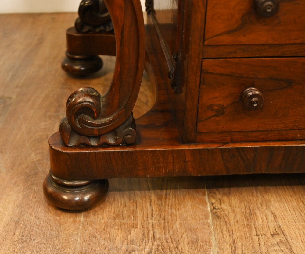 A Victorian mahogany Davenport desk featuring a sloped leather writing top, carved cresting rail, serpentine front supports, and side drawers. View VII