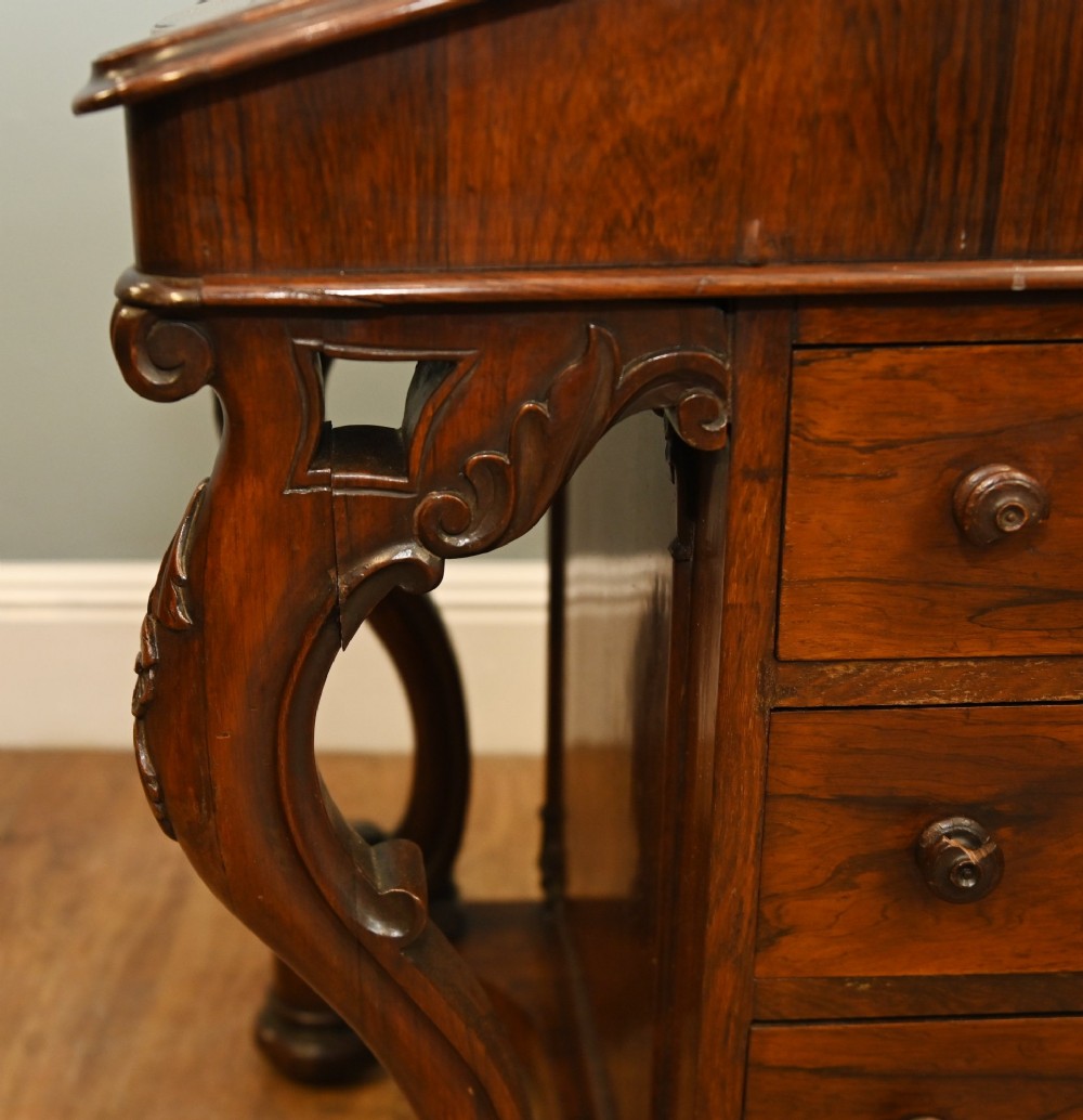 A Victorian mahogany Davenport desk featuring a sloped leather writing top, carved cresting rail, serpentine front supports, and side drawers. View VIII