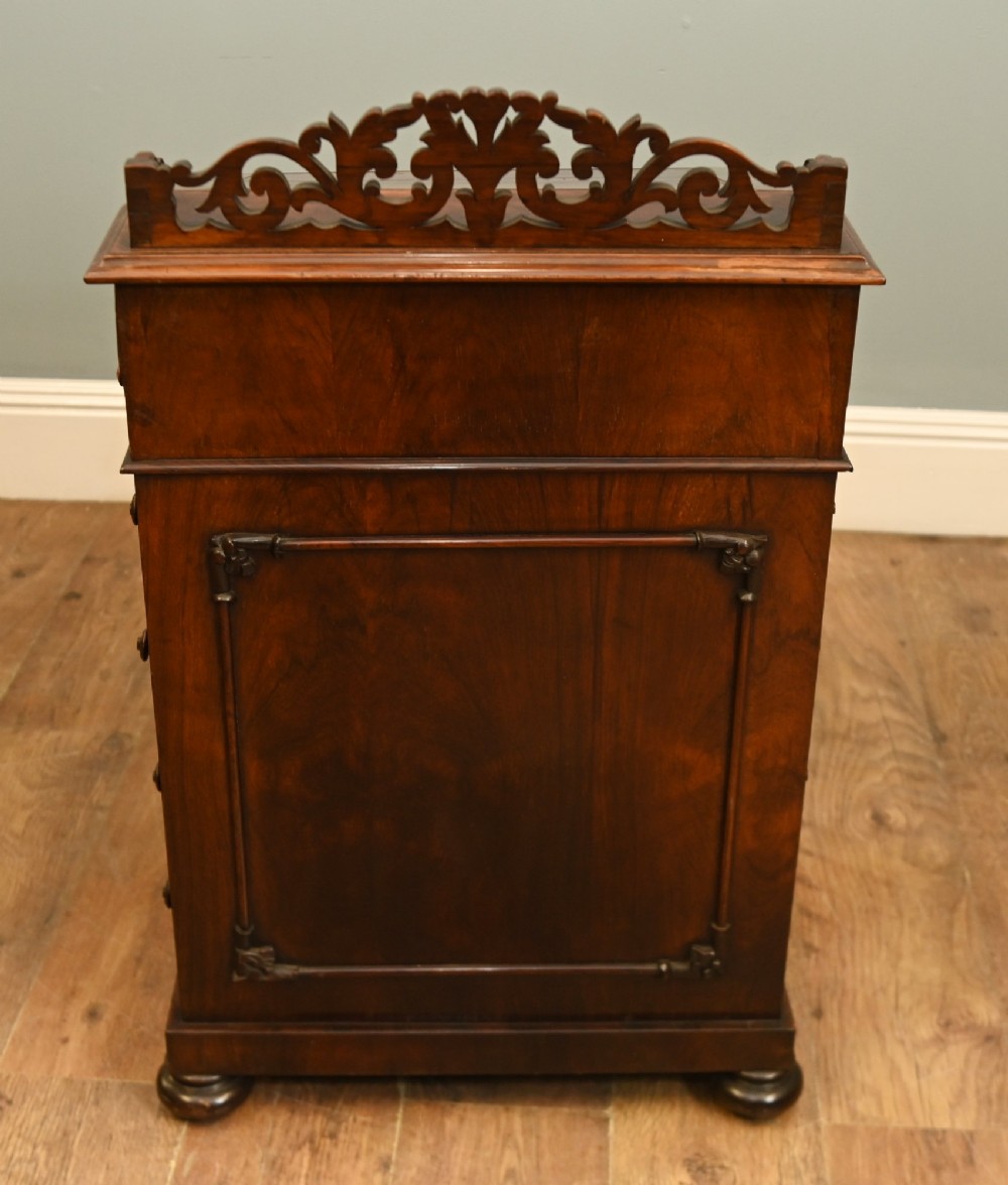 A Victorian mahogany Davenport desk featuring a sloped leather writing top, carved cresting rail, serpentine front supports, and side drawers. View IX