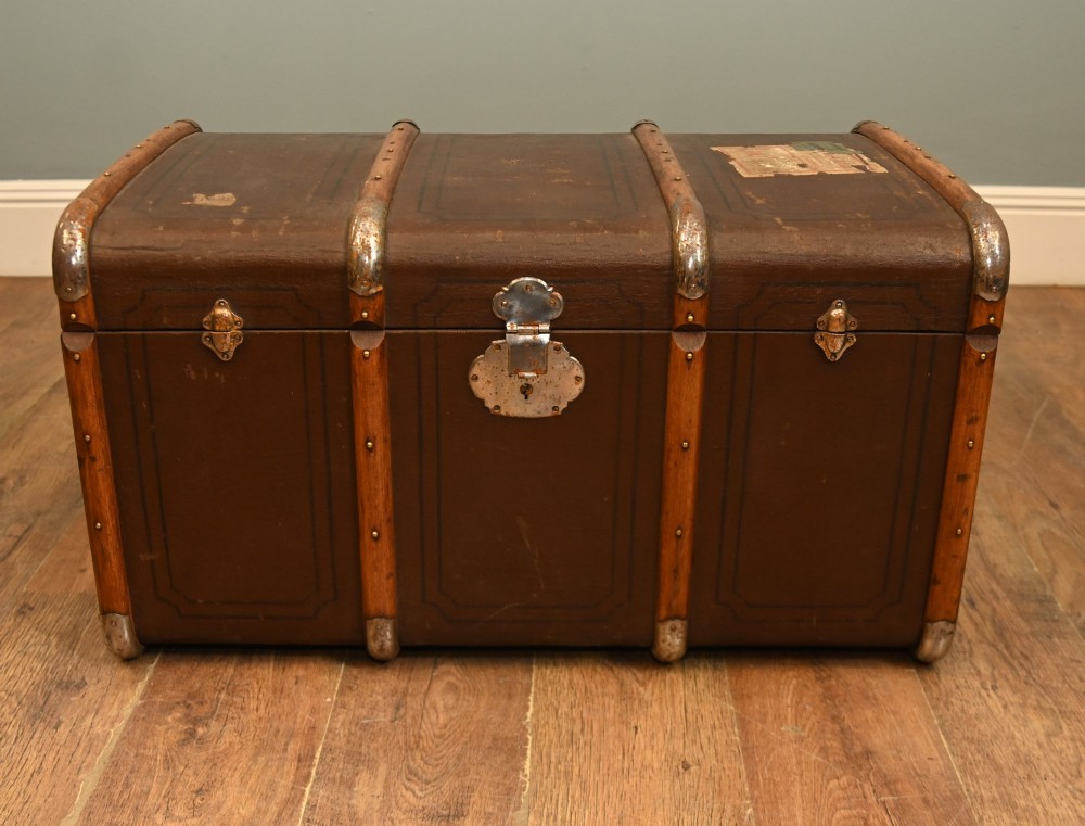 A dark brown 1920s antique steamer trunk with wooden slats, corner brackets, and a central metal latch.