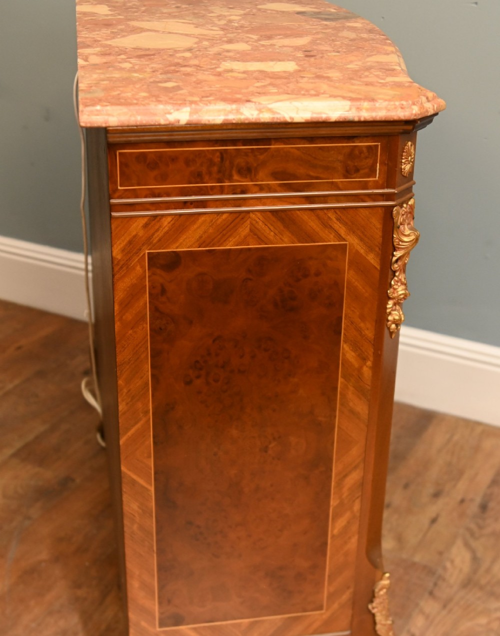 A Louis XV Revival walnut side cabinet featuring a serpentine front, floral marquetry inlay, pink marble top, and gilt-bronze mounts on cabriole legs. View XI