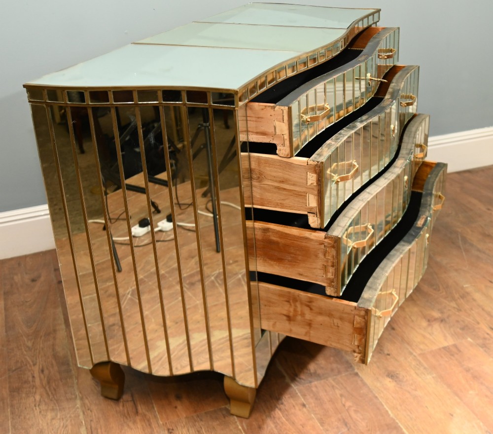 An Art Deco mirrored chest of drawers featuring segmented glass panelling, four drawers with geometric brass handles, and a shaped lower apron. View VII
