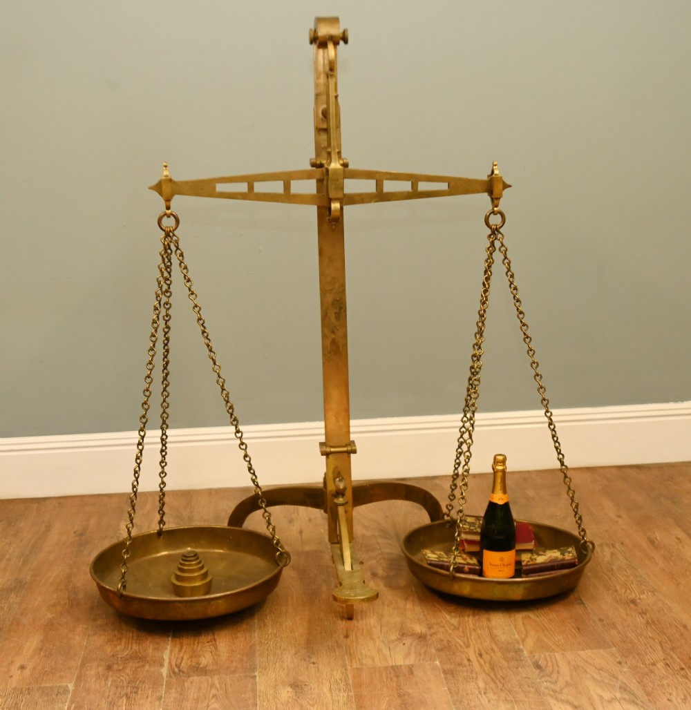 A nineteenth-century brass Avery balance scale featuring a tall central pillar, horizontal beam, twin hanging circular pans, and nested counterweights.