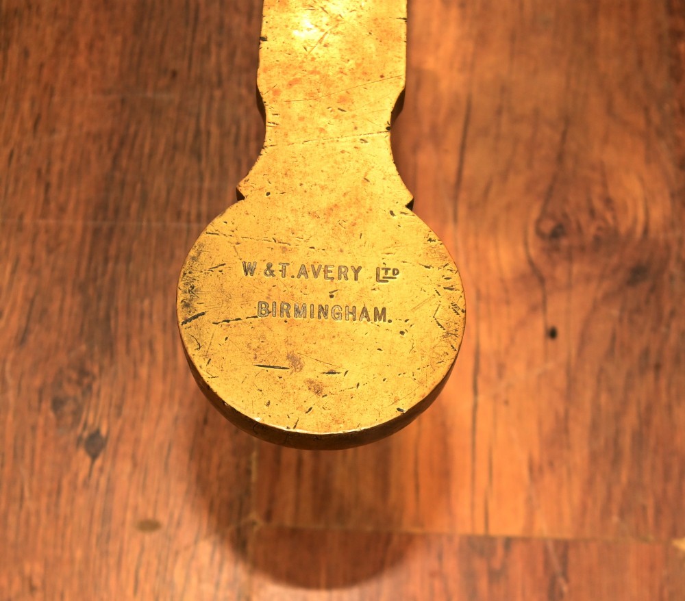 A nineteenth-century brass Avery balance scale featuring a tall central pillar, horizontal beam, twin hanging circular pans, and nested counterweights. View V