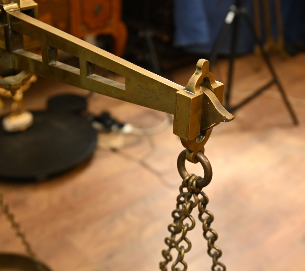 A nineteenth-century brass Avery balance scale featuring a tall central pillar, horizontal beam, twin hanging circular pans, and nested counterweights. View X