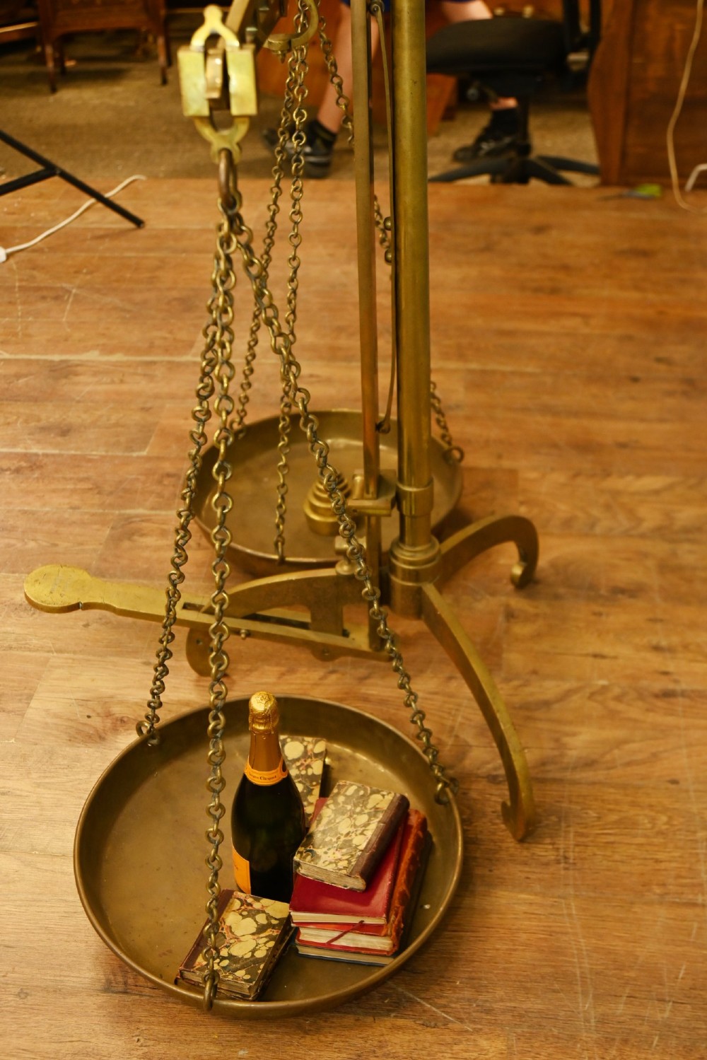 A nineteenth-century brass Avery balance scale featuring a tall central pillar, horizontal beam, twin hanging circular pans, and nested counterweights. View XII
