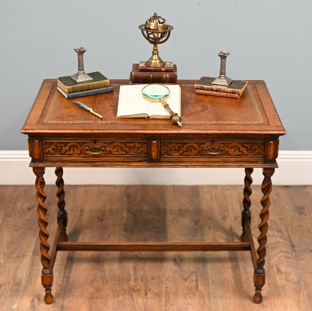 A Victorian oak writing desk featuring barley twist legs, carved apron detailing, a leather inset writing surface, and an H-stretcher. View II