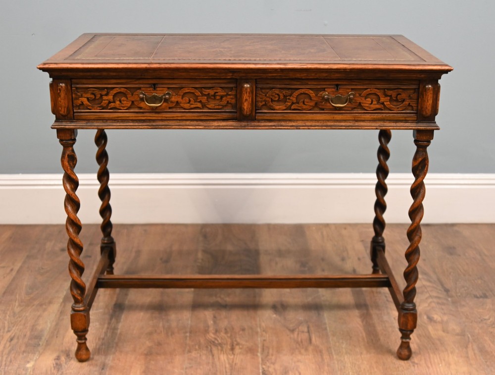 A Victorian oak writing desk featuring barley twist legs, carved apron detailing, a leather inset writing surface, and an H-stretcher. View III