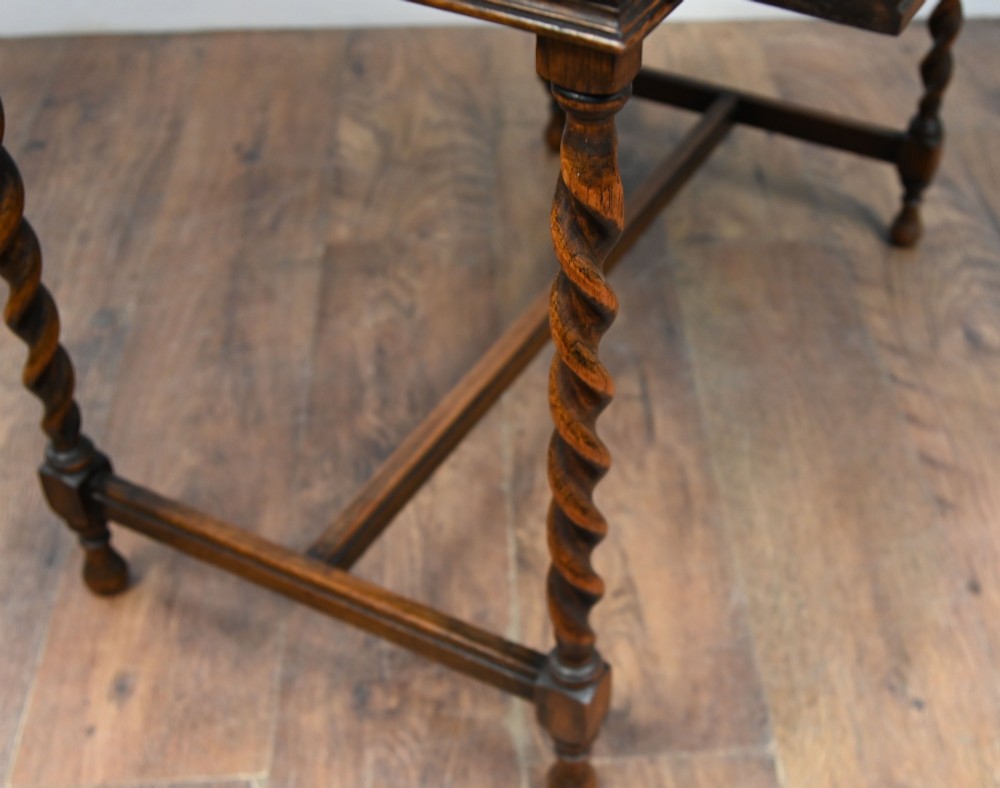 A Victorian oak writing desk featuring barley twist legs, carved apron detailing, a leather inset writing surface, and an H-stretcher. View VIII