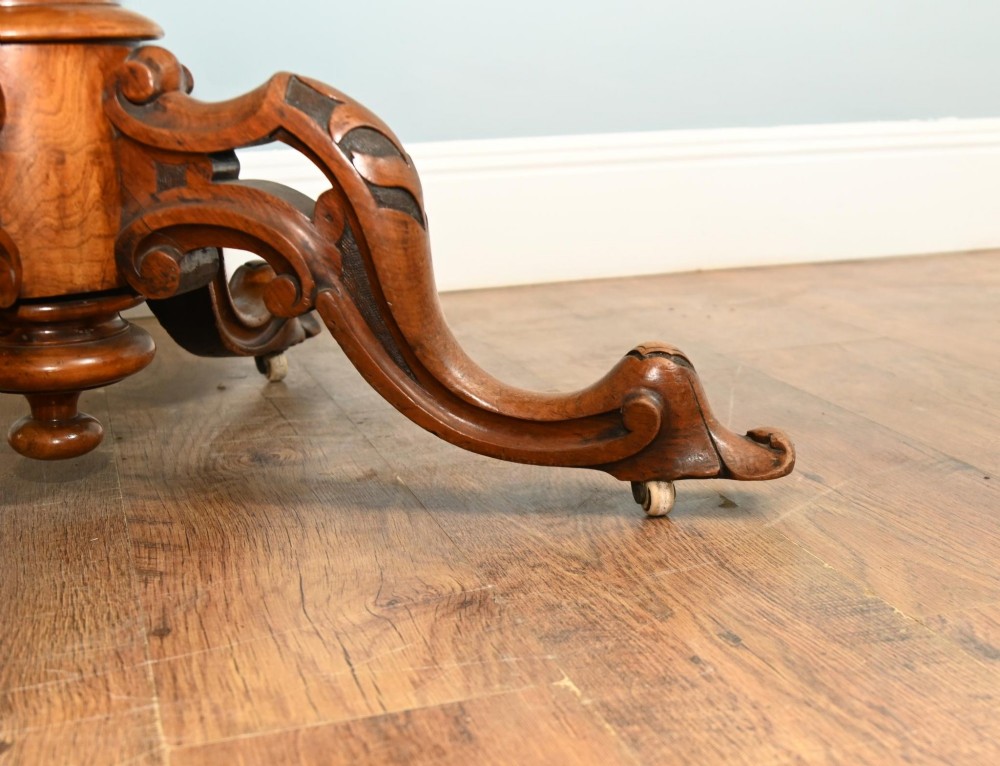 A mid-19th-century Irish burr walnut centre table featuring a shaped serpentine top with a carved frieze set on a turned pedestal with four carved legs. View II