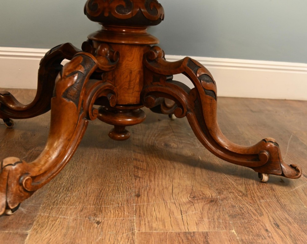 A mid-19th-century Irish burr walnut centre table featuring a shaped serpentine top with a carved frieze set on a turned pedestal with four carved legs. View VII