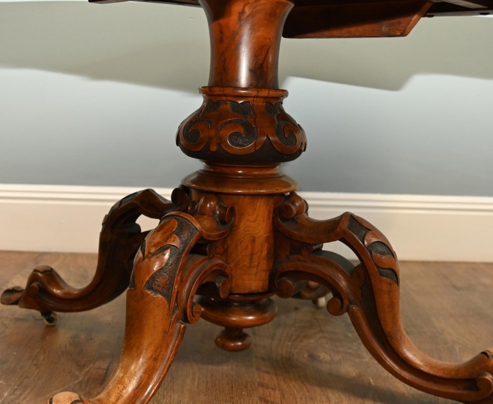 A mid-19th-century Irish burr walnut centre table featuring a shaped serpentine top with a carved frieze set on a turned pedestal with four carved legs. View VIII