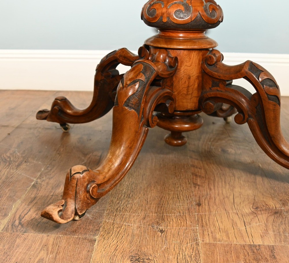 A mid-19th-century Irish burr walnut centre table featuring a shaped serpentine top with a carved frieze set on a turned pedestal with four carved legs. View IX