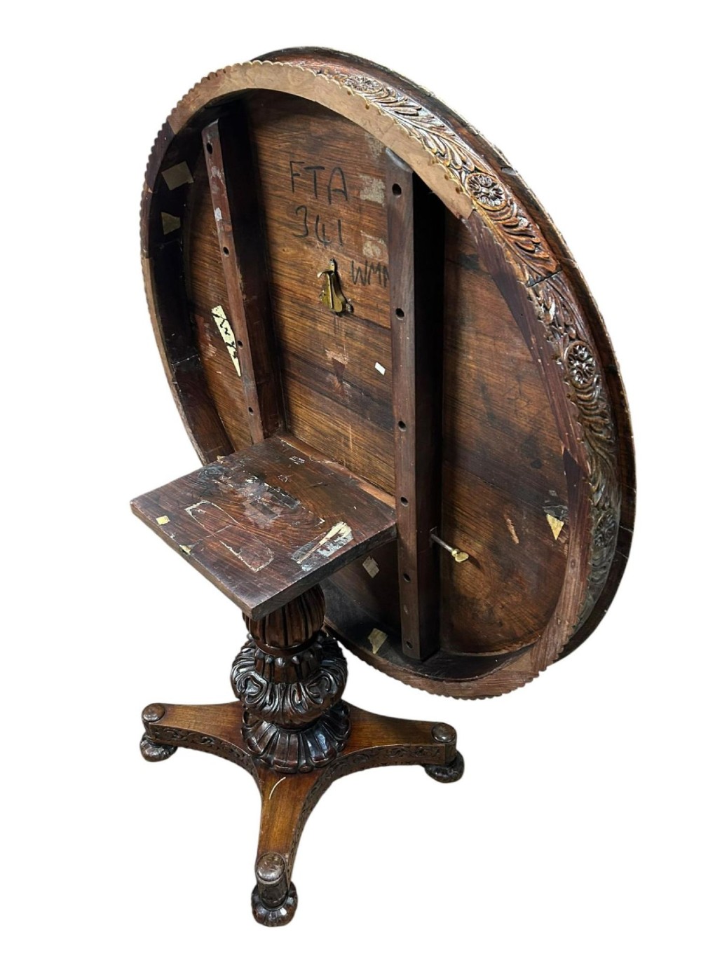 A round antique Burmese hardwood dining table featuring a polished top, an intricately carved apron, and a central pedestal base with tripod legs. View VII