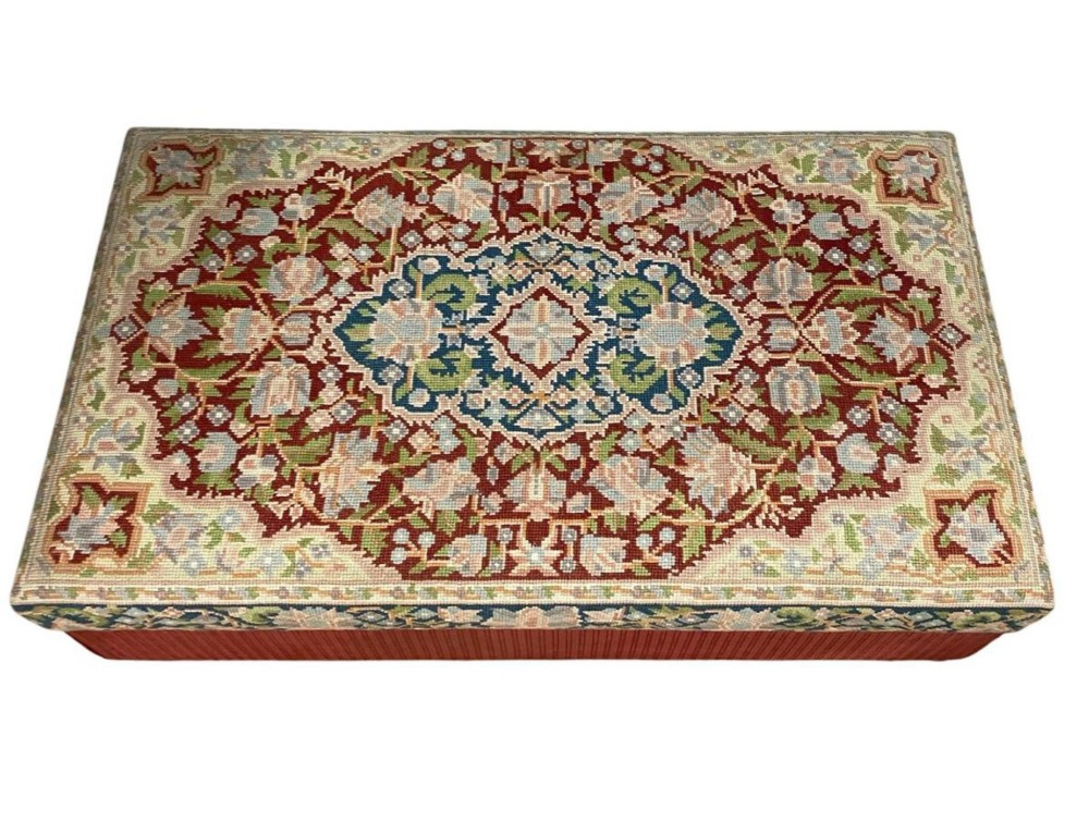 A low rectangular ottoman featuring a central multi-coloured floral needlepoint tapestry top bordered by red velvet side fabric with a pull tab. View II