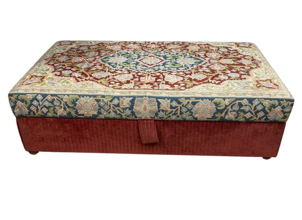 A low rectangular ottoman featuring a central multi-coloured floral needlepoint tapestry top bordered by red velvet side fabric with a pull tab. View VII