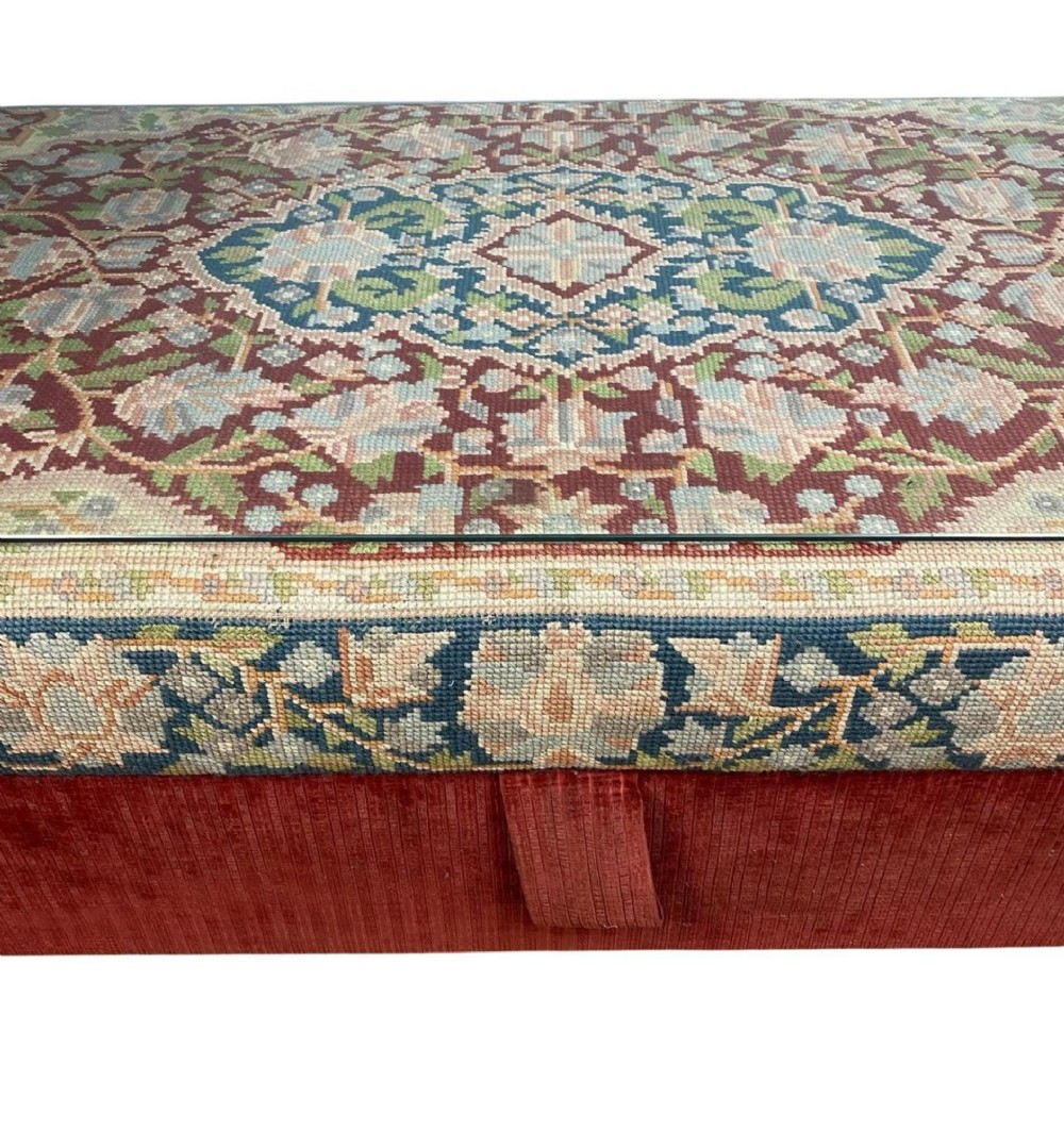 A low rectangular ottoman featuring a central multi-coloured floral needlepoint tapestry top bordered by red velvet side fabric with a pull tab. View X