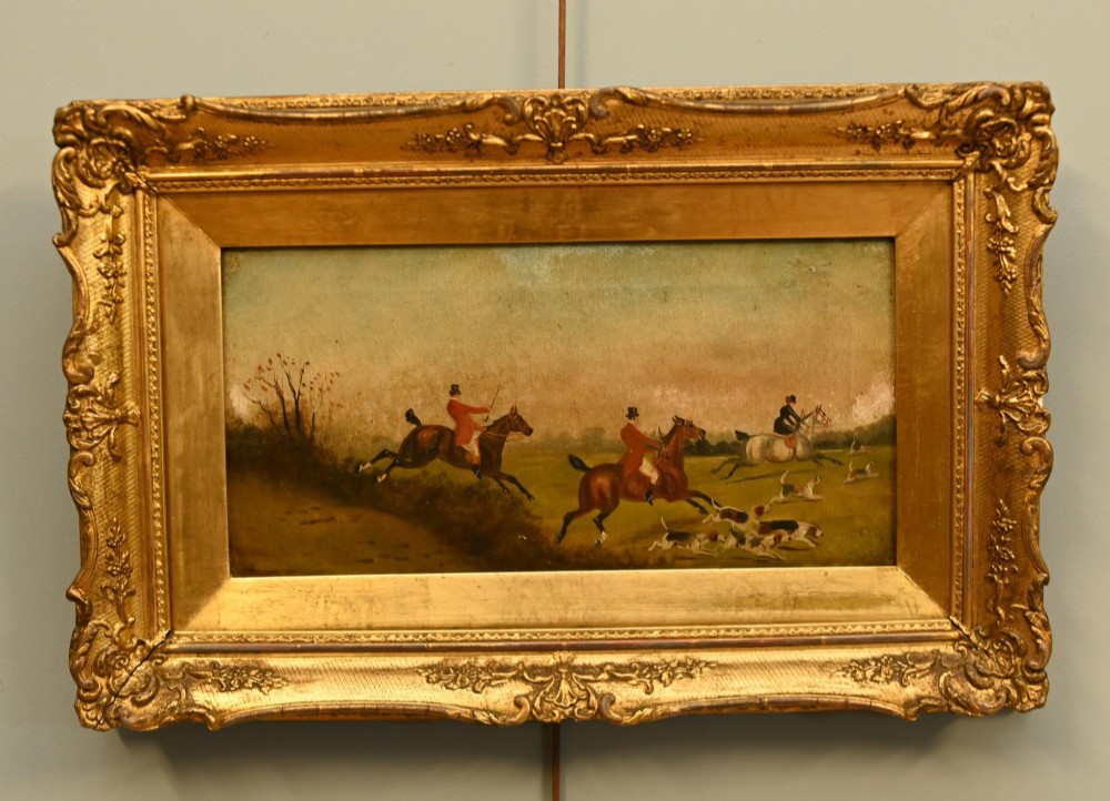 A pair of horizontal antique Victorian oil paintings in ornate gold gilt frames depicting horseback riders and hounds in a field. View III