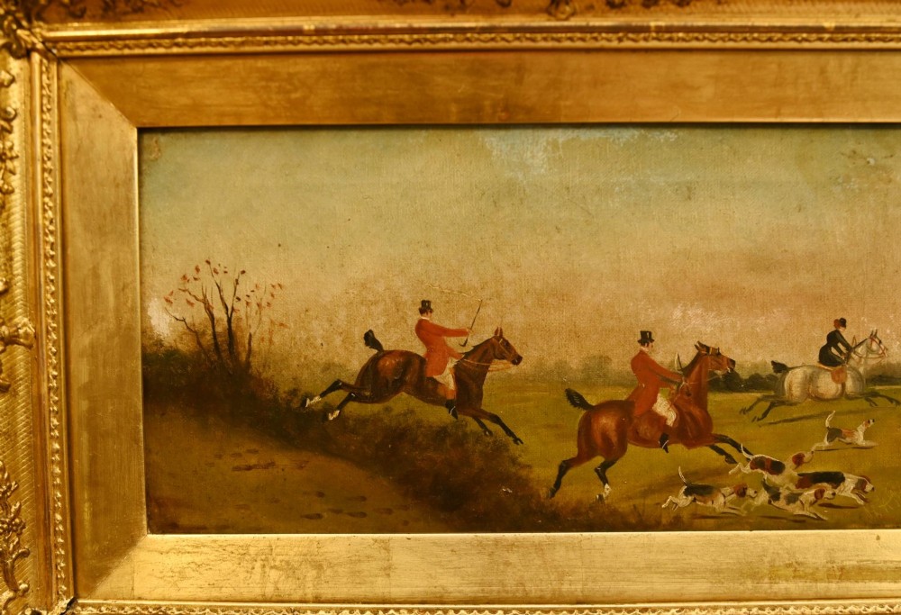 A pair of horizontal antique Victorian oil paintings in ornate gold gilt frames depicting horseback riders and hounds in a field. View IV