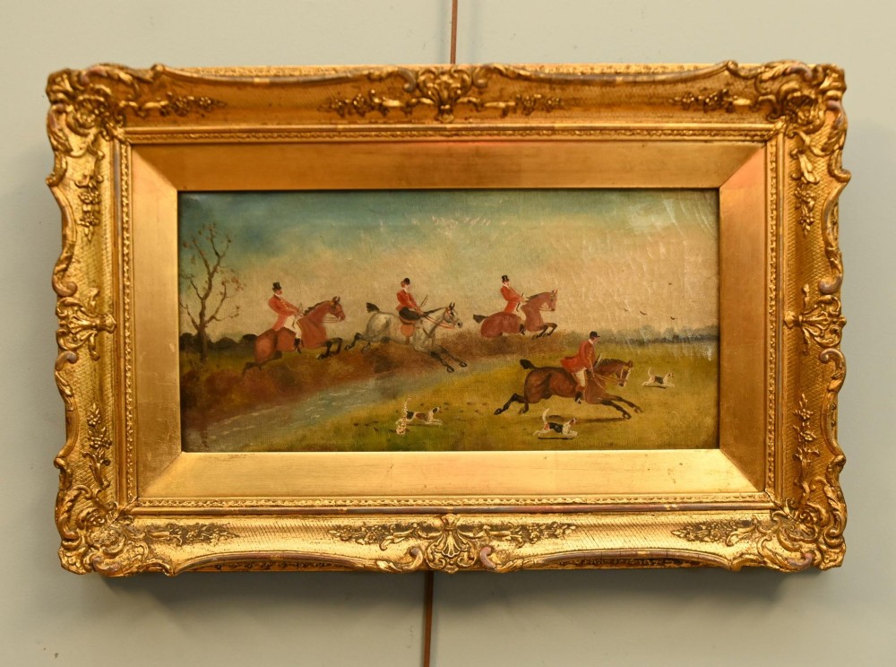 A pair of horizontal antique Victorian oil paintings in ornate gold gilt frames depicting horseback riders and hounds in a field. View IX