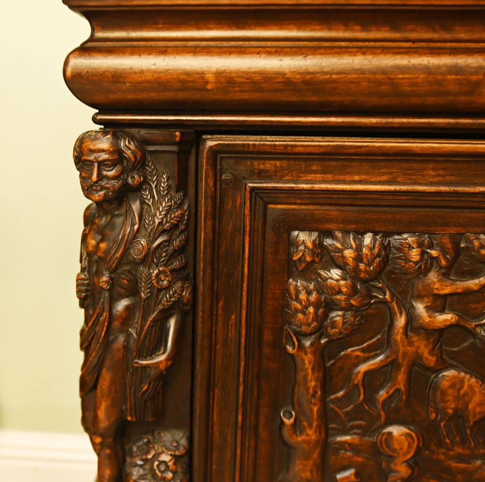 A carved dark walnut coffer featuring a central relief scene flanked by carved corner figures and decorative egg-and-dart base mouldings. View II