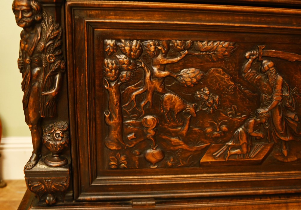 A carved dark walnut coffer featuring a central relief scene flanked by carved corner figures and decorative egg-and-dart base mouldings. View III