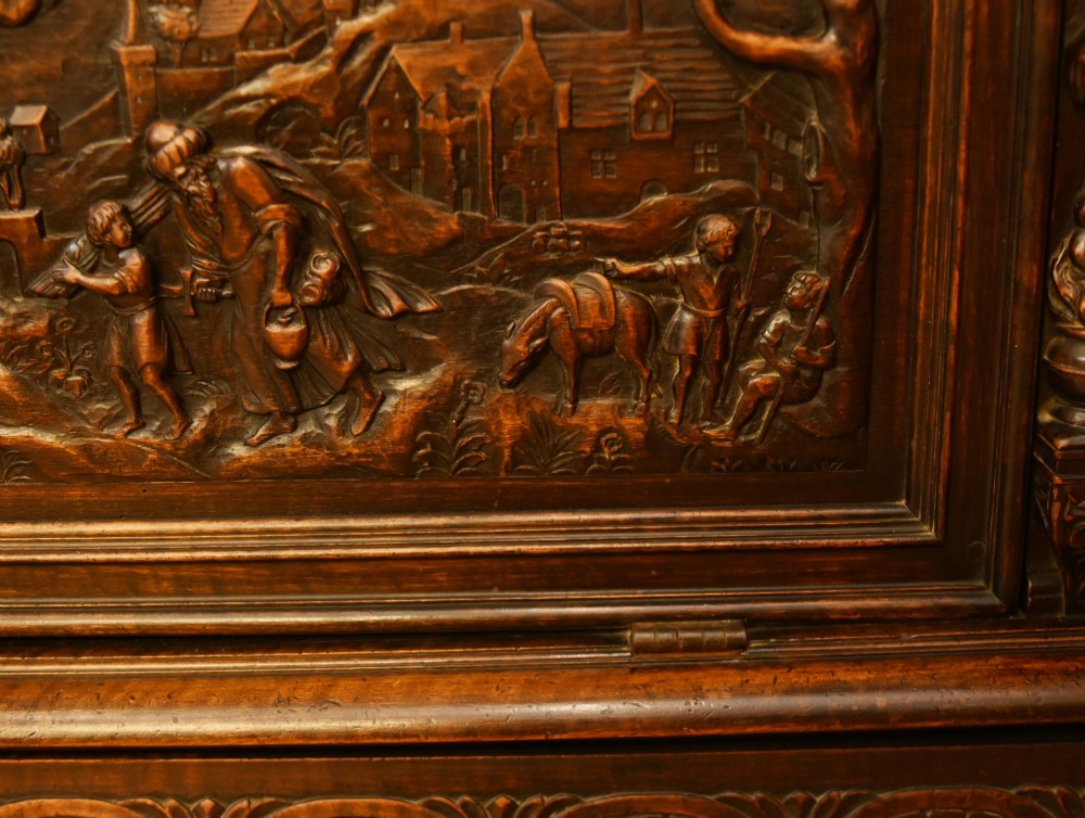 A carved dark walnut coffer featuring a central relief scene flanked by carved corner figures and decorative egg-and-dart base mouldings. View VI