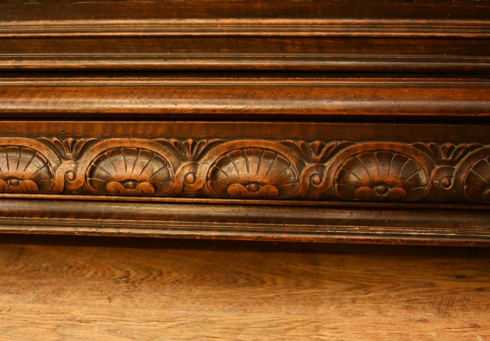 A carved dark walnut coffer featuring a central relief scene flanked by carved corner figures and decorative egg-and-dart base mouldings. View VIII