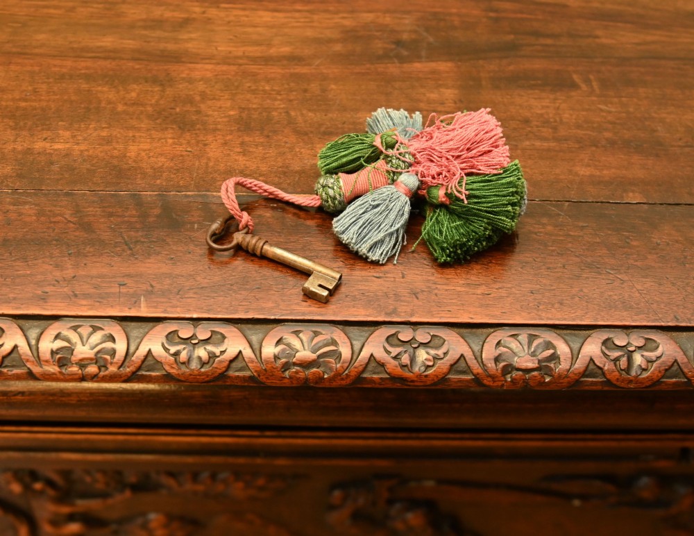 A carved dark walnut coffer featuring a central relief scene flanked by carved corner figures and decorative egg-and-dart base mouldings. View IX